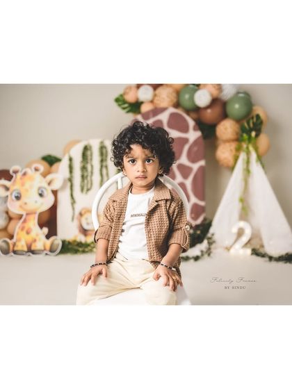 A handsome two-year-old posing for his birthday portrait. The safari theme with a cute giraffe and tent is perfect for a little adventurer.
