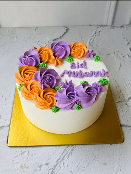 A classic Eid Mubarak cake decorated with a crescent of vibrant orange and purple buttercream roses. It's a beautiful and festive addition to your Eid feast.