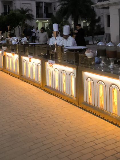 A closer look at our illuminated buffet counters, ready for service. The setup includes a beverage station and a variety of main courses, all presented with our signature elegance.