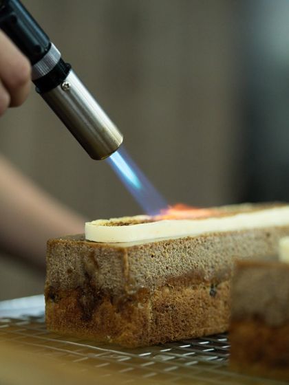 Using a torch to caramelize a travel cake, one of the many modern finishing techniques covered in our corporate programs.