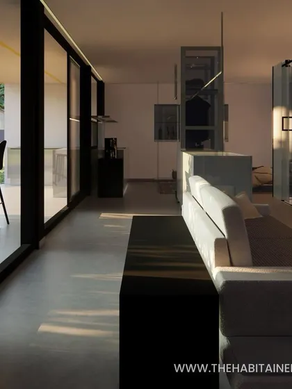 The interior of the container studio at sunset, with light streaming through the large glass walls. This render highlights the open and airy feeling of the space.
