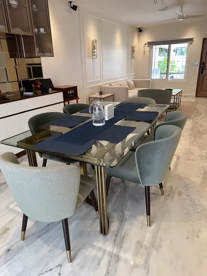 An open-plan living and dining area where our furniture creates a cohesive flow. The dining set in the foreground complements the living room furniture in the background, showcasing our ability to furnish an entire luxury residence.