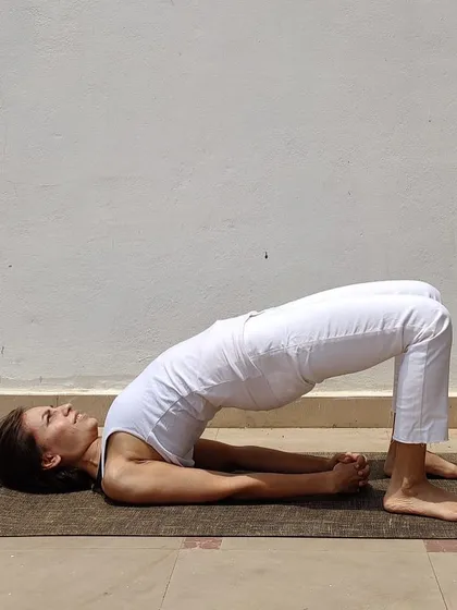 Setu Bandhasana, or Bridge Pose, is a gentle backbend that strengthens the glutes and opens the chest. A great tip for beginners is to place a block between the thighs to keep the knees from splaying out.