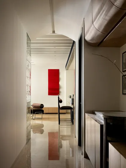The passage leading from the bedroom to the living room feels like a gallery, with a bold red metal art piece and a softly rippled arched ceiling.