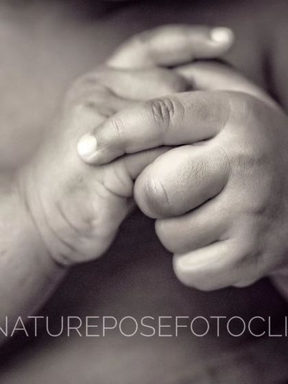A macro shot of a newborn's clasped hands, showcasing the delicate wrinkles and perfect little fingernails.