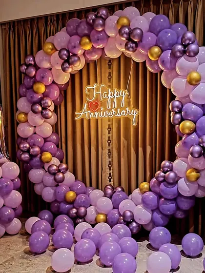 This unique purple and gold balloon arch was designed for a first anniversary. The color combination offers a stylish and less traditional option for your celebration, complete with a marquee number and neon sign.