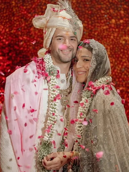 Capturing the joy of the newly married couple amidst the decor we created for them. This moment, showered in petals against a backdrop of rich red florals, is why we do what we do.