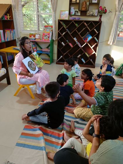 The storyteller shows a picture of a forest, using the story to talk about nature and the environment.