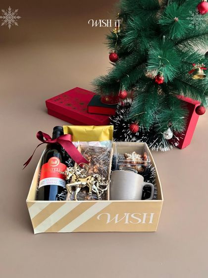 Our "Holiday Crate" sitting pretty under a Christmas tree. It's filled with wine, a festive mug, an ornament, and other treats to get you in the holiday spirit.