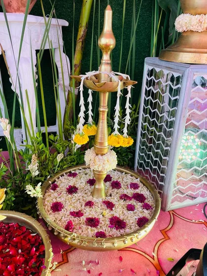 A detailed shot of a traditional brass 'diya' placed in a bowl of rice and flower petals, an important element in many Indian ceremonies.