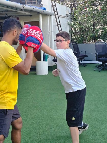 A young athlete practices a straight punch, aiming for the center of the pad. This drill hones hand-eye coordination and teaches the fundamentals of generating power from the ground up.