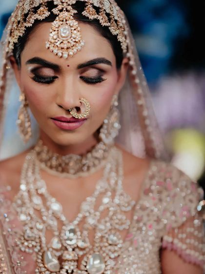 A detailed makeup and jewelry shot of a bride. The focus is on the flawless makeup and the intricate nath and matha patti, showing my attention to every detail.