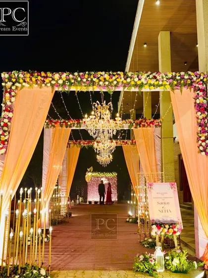 A beautiful entrance sets the tone for the entire evening. Here, I combined elegant peach-colored drapes, intricate floral arrangements, warm candle-like lighting, and grand chandeliers to create a welcoming and luxurious entryway for the guests.