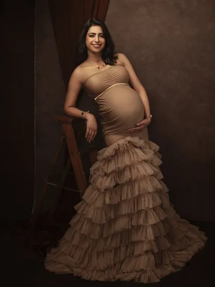 Posed with grace and poise, this portrait showcases the full length of the beautiful gown against a classic, textured backdrop, creating a truly timeless image.