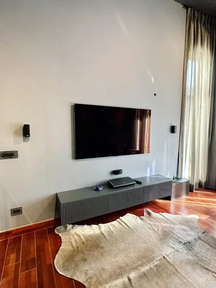 This image shows the media wall opposite the sofa, featuring a minimalist floating TV console. This choice keeps the floor clear, enhancing the sense of space, and provides a clean, uncluttered look that complements the room's modern aesthetic.