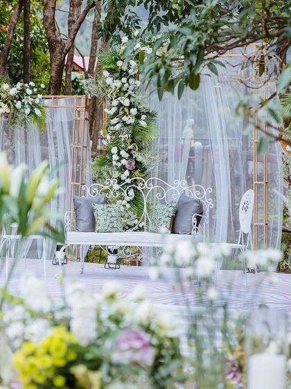 A detail shot of the elegant white seating and floral arrangements for an outdoor wedding ceremony.