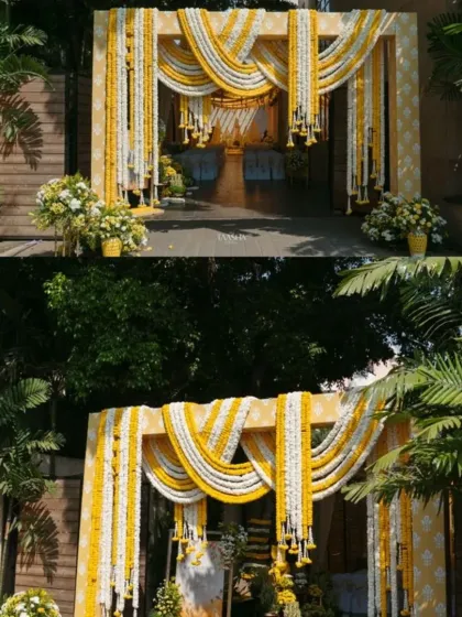 A grand entrance for a home-based Haldi ceremony. The structure is heavily decorated with garlands of yellow and white flowers, creating a welcoming and auspicious entryway.