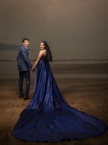 A glamorous shot on the beach, with the long trail of a blue gown creating a sense of drama and elegance.