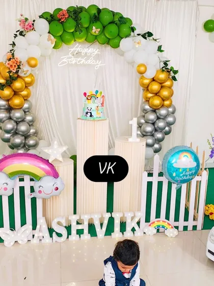 This photo shows a complete decoration setup for a first birthday party. I arranged the rainbow and animal-themed decor, including the balloon arch, custom name blocks, and cake stands, to create a perfect photo-ready scene for the celebration.