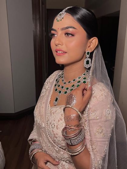 The combination of the soft pastel outfit and the striking green jewelry is simply perfect.