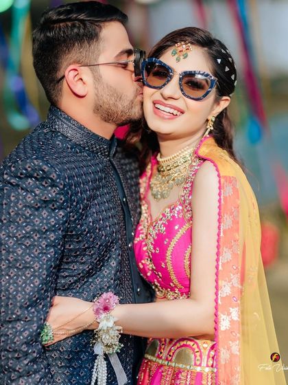 A sweet and spontaneous kiss on the cheek from the groom during the Mehendi, capturing a moment of affection amidst the festivities.
