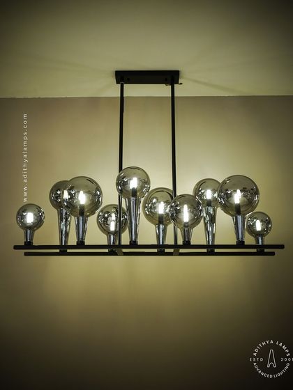 A playful yet chic linear chandelier featuring a series of chrome-finished glass bubbles. The highly reflective surface and modern design make it a striking addition to a kitchen island or a contemporary dining space.