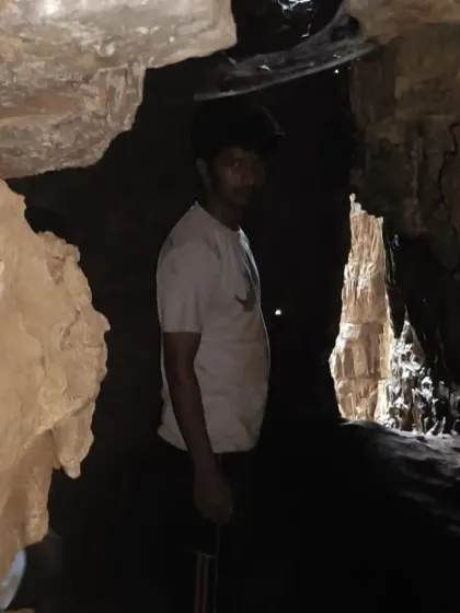 A trekker looking out from a dark passage within the cave.