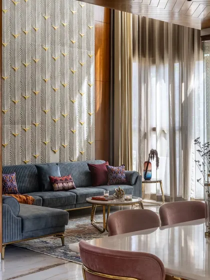 In the living area of the Avani Residence, sunlight streams through double-height windows, illuminating a custom-carved stone panel inspired by peacock feathers. This space is a testament to our philosophy of using light as a key design element to create evolving, artistic interiors.