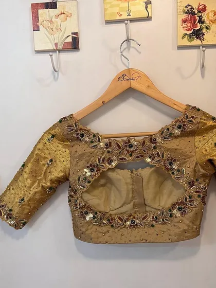The back of the gold Kanjeevaram bridal blouse, featuring a floral-bordered cutout design that is both traditional and stylish.