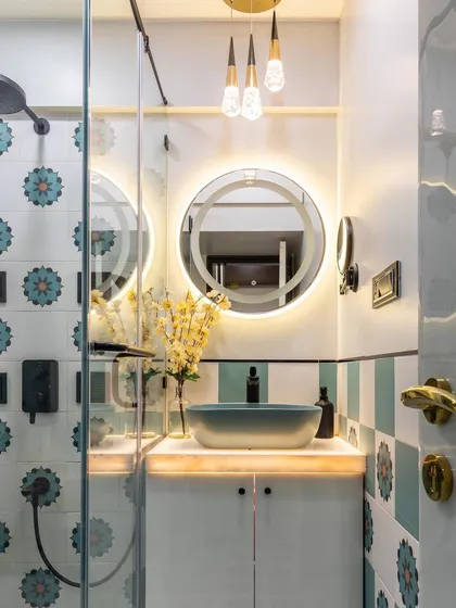 Elevate your bathroom with thoughtful details. This design features beautiful floral tiles, a backlit round mirror, and elegant pendant lights to create a space that feels like a personal spa.