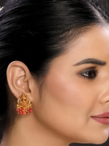 This image captures the detail of traditional temple earrings with red beadwork. The model's simple styling ensures the jewellery is the main focus, suitable for catalogue and online store use.
