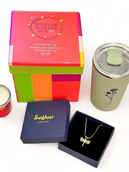 A Women's Day gift set featuring a beautiful dragonfly necklace, a scented candle, and a stylish sipper, all packed in a colorful box.