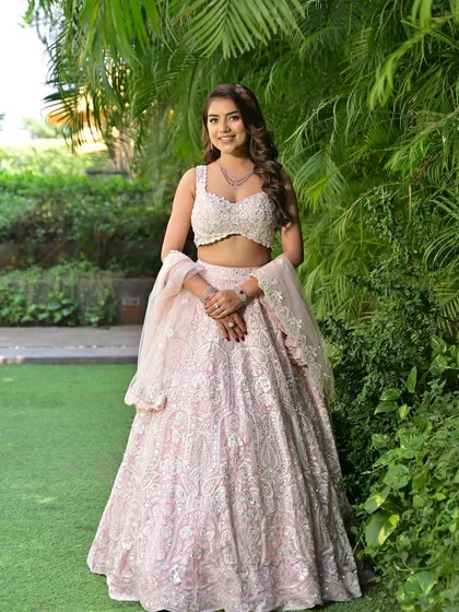 A full-length shot of the bride in her stunning pink lehenga, looking like a princess in a garden.