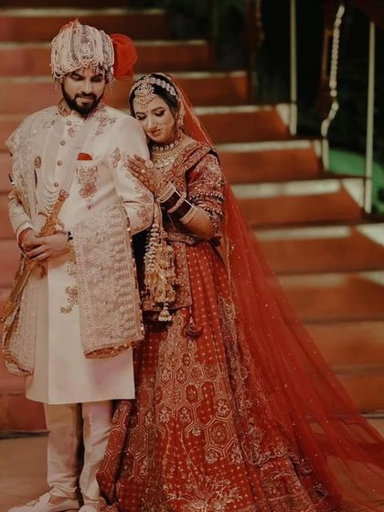 A beautiful couple portrait. The bride's red lehenga with the long train looks so grand.
