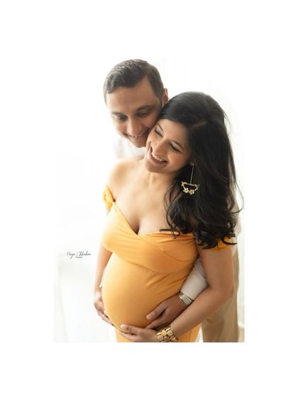 The pure joy of the journey together. This close-up shot focuses on the couple's happy expressions and the protective embrace around the baby bump.