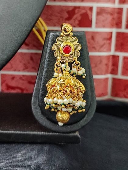 The matching earring for this set, featuring a floral top and a delicate jhumka.