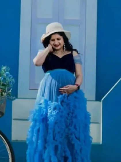Our blue ruffled gown features a velvet bodice and a full tulle skirt, offering a unique mix of textures. It's a wonderful choice for a themed maternity shoot, shown here with a charming bicycle prop.