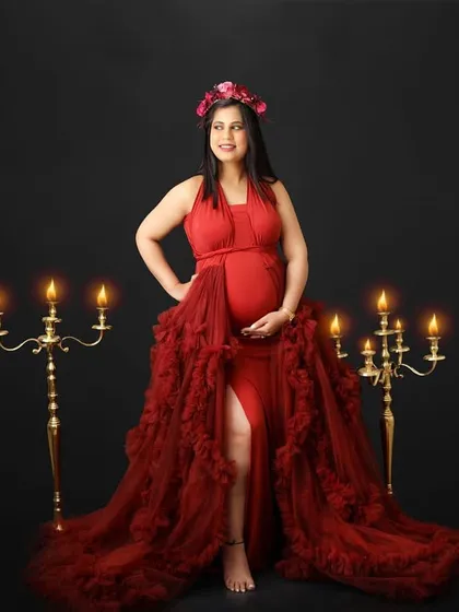 Framed by the warm glow of candelabras, this mom-to-be shines in a bold red gown. This shot is all about celebrating pregnancy with confidence and glamour.