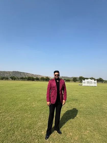 Client Mr. Avi Singal stands confidently in a striking red blazer, a bold choice for an outdoor event.