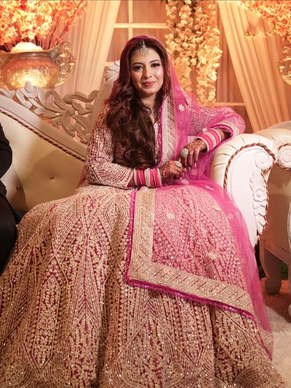 A full-length shot of the bride on her Walima day. The intricate details of her pink lehenga are complemented by her soft and glamorous makeup.
