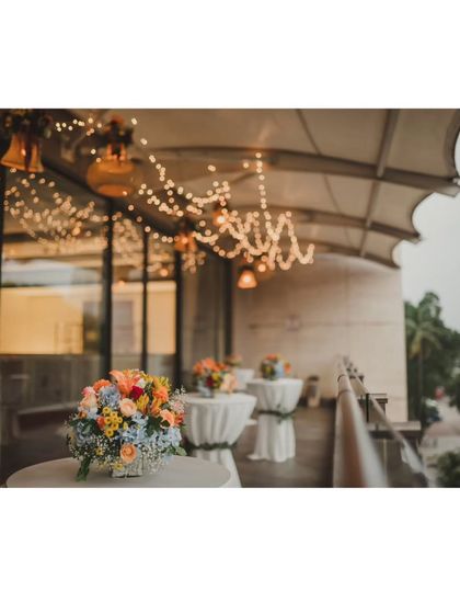 The cocktail table setup on a balcony, with fairy lights and hanging lamps creating a cozy and inviting atmosphere for guests to mingle.