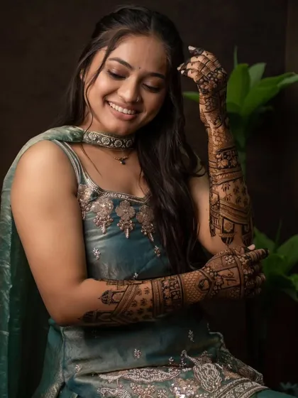 The result of our work is a happy bride. Here she is, glowing and showing off her full-arm bridal mehandi, which is rich in detail and features traditional wedding scenes. We promise a deep, beautiful stain every time.