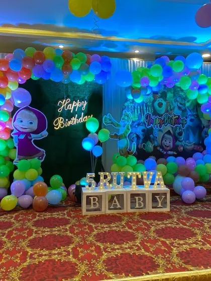 The main stage for the Masha and the Bear party, featuring character cutouts and a balloon arch against a green backdrop.