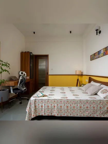 An earthy and minimal bedroom in our Banashankari project. We used cool Kota stone flooring, a simple color palette with a pop of yellow, and a bay window seat to create a comfortable and grounded personal space that feels both modern and timeless.