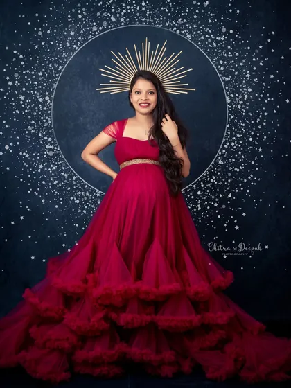 Celestial and radiant. This stunning magenta gown with a tiered skirt, paired with a celestial halo prop, creates a truly magical and artistic pregnancy portrait.