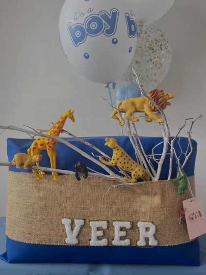 A closer look at the safari animal details and the rustic burlap and royal blue fabric covering the hamper for Veer.