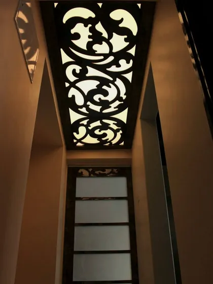 An ornate ceiling panel with backlighting, creating a dramatic and luxurious effect in a hallway or entryway.