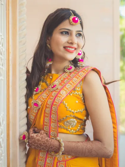 A beautiful portrait of a bride in her Haldi ceremony attire. The bright yellow saree and floral jewelry are perfectly captured in this happy, sun-kissed shot.