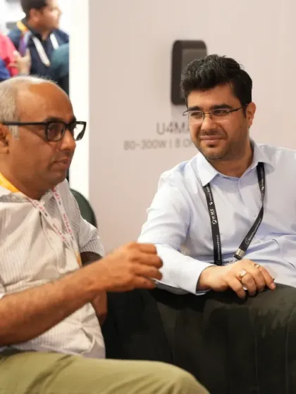 A relaxed yet productive meeting takes place at an exhibitor's booth. The expo environment is designed to foster both formal and informal networking opportunities.