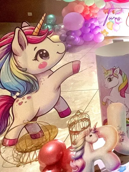 A life-sized cutout of a dancing unicorn adds a playful element to the decor, complemented by other themed props like a golden birdcage.